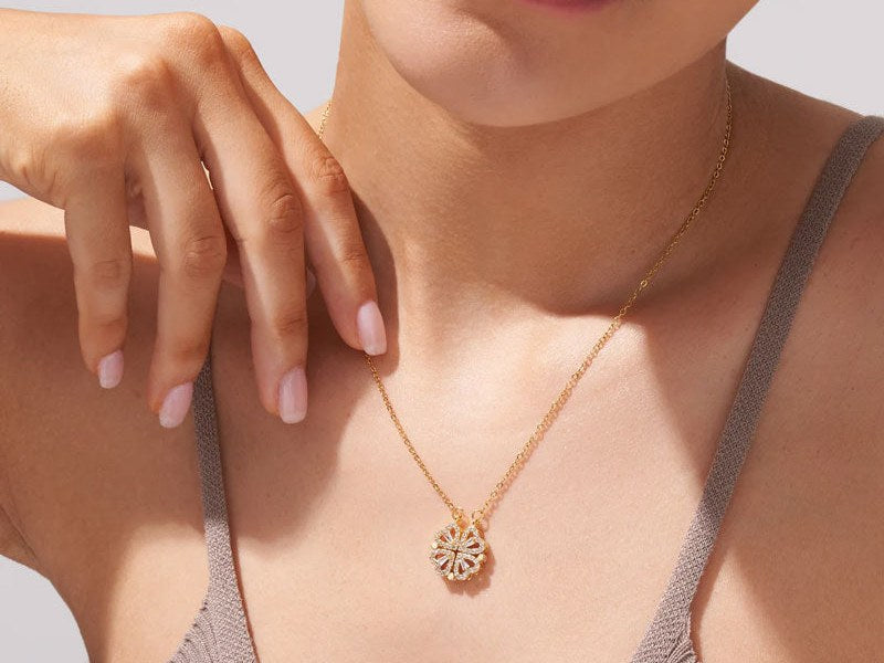 Fingertips resting on the clover pendant at the collarbone