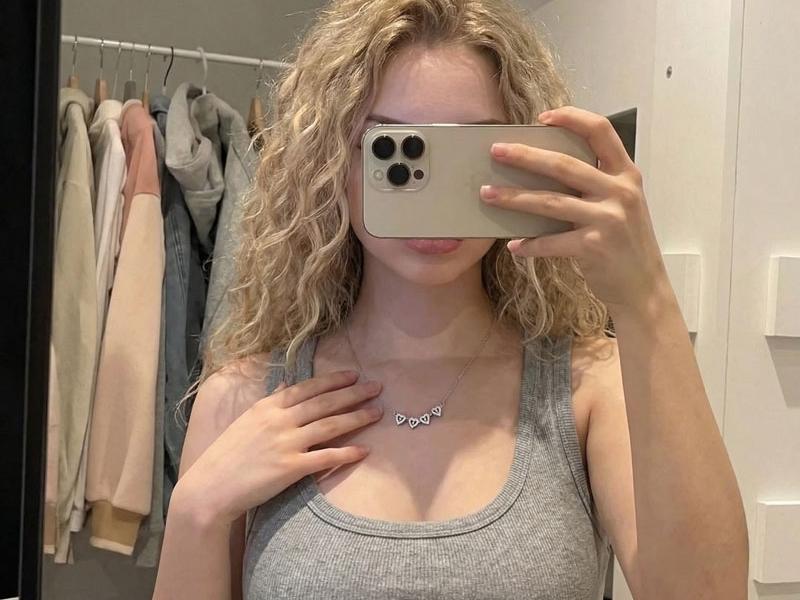 A granddaughter wearing the clover necklace, phone in hand