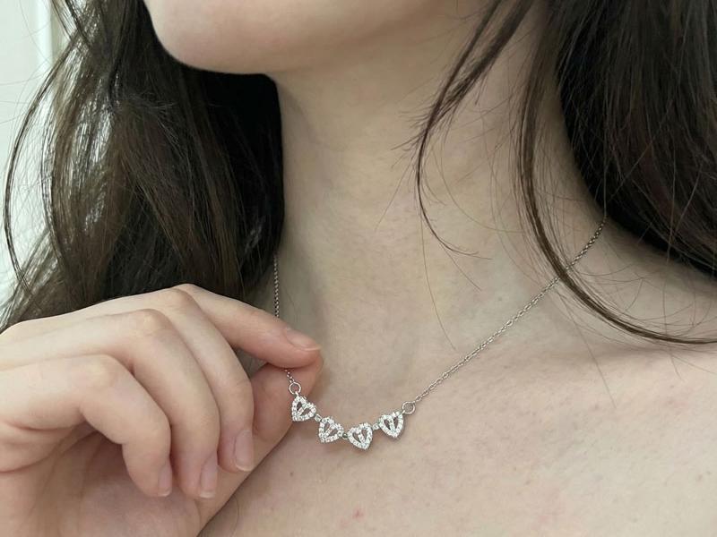 A young woman holding the four hearts at her neck